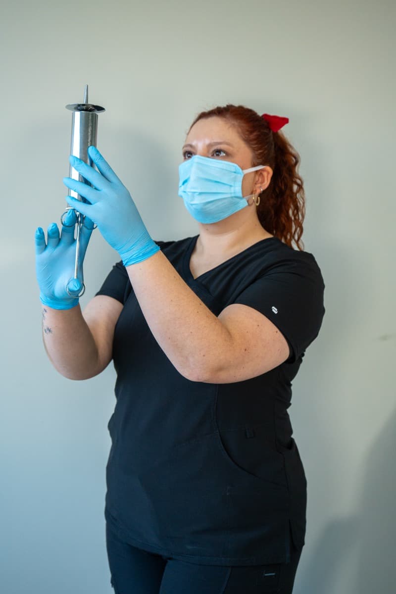 Profesional de audiología realizando procedimiento con equipamiento moderno y medidas de seguridad, mostrando el uso correcto de EPP y tecnología avanzada